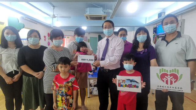 基金会主席林城礼先生(右四)在刘长武牧师(右一)及小飞鹰院长黄声志女士(右二)及师生的见证下,将医药费移交给黄尉贵(左前)的家人。左三为婆婆盤金玉女士,爸爸黄信翔先生(左四)。